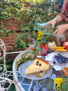 mesa de merienda en el jardín con tarta de queso y frutas