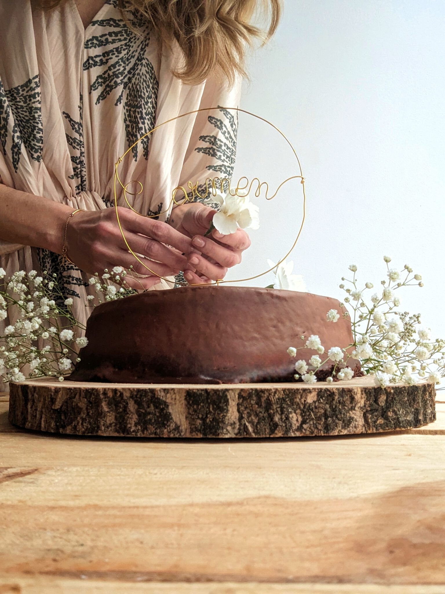 Mujer decorando con flores una Fudge Cake, nuestra tarta de chocolate